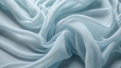 The primary subject of the image is a blue sheet of fabric, which is the main object, scene, or focus of the image. The setting or background is a white surface, and the visual style is a photo. The colors and mood of the image are predominantly blue, creating a calm and serene atmosphere.