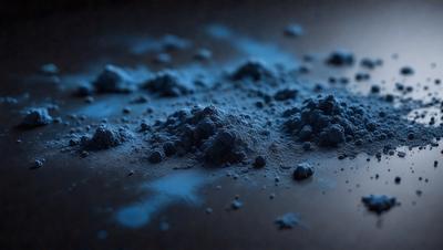 The primary subject of the image is a blue substance, possibly a powder or a liquid, spread across a surface. The setting appears to be a dark room, with the blue substance being the main focus of the image. The visual style is a close-up of the blue substance, which gives the image a somewhat surreal or artistic appearance. The colors and mood of the image are predominantly blue, creating a calm and serene atmosphere.