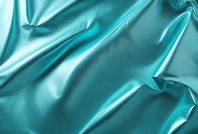The primary subject of the image is a blue fabric, possibly a piece of silk, with a shiny and smooth texture. The setting is a close-up view of the fabric, showcasing its intricate details. The visual style is a realistic representation of the fabric, capturing its true colors and appearance. The dominant colors in the image are blue and silver, creating a calm and serene atmosphere.