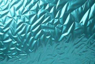 The primary subject of the image is a blue fabric with a pattern of triangles. The setting is a blue background, and the visual style appears to be a photo. The dominant colors are blue and silver, creating a calm and soothing atmosphere.