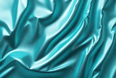 The primary subject of the image is a close-up of a blue fabric, possibly a piece of silk or satin. The setting is a background of a blue fabric, which creates a cohesive and visually appealing scene. The visual style is a close-up of the fabric, showcasing its texture and details. The colors and mood of the image are predominantly blue, giving it a calm and serene atmosphere.
