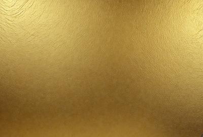 The primary subject of the image is a close-up of a shiny, golden surface. The setting is a wall, and the visual style is a photo. The dominant colors are gold and brown, creating a warm and shiny atmosphere.