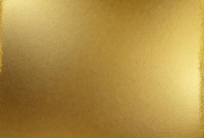 The primary subject of the image is a large, shiny, and golden wall. The setting is a room with a gold-colored wall, which serves as the background. The visual style of the image is a close-up of the wall, showcasing its texture and color. The dominant colors in the image are gold and brown, creating a warm and luxurious atmosphere.