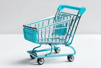 The primary subject of the image is a blue shopping cart. The cart is placed on a white surface, which serves as the background. The visual style of the image is a photo, capturing the cart in its natural environment. The dominant colors in the image are blue and white, creating a clean and modern atmosphere.