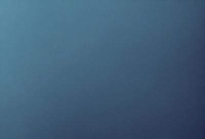 The primary subject of the image is a large, dark blue sky. The setting is a vast, open space with no visible landmarks or objects. The visual style is a natural, untouched environment. The colors and mood are predominantly dark and moody, with the blue sky serving as the main focal point.