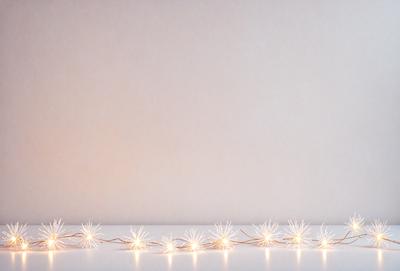 The primary subject of the image is a string of lights, which are illuminated and create a visually appealing display. The lights are arranged in a row, creating a sense of depth and dimension. The setting is a white wall, which serves as a clean and uncluttered backdrop for the lights. The visual style of the image is a combination of digital art and illustration, as the lights are depicted in a realistic manner while still maintaining a sense of artistic expression. The colors and mood of the