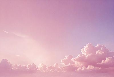 The primary subject of the image is a cloudy sky with a pink hue. The setting is a beautiful, cloudy day with a purple sky. The visual style is a natural, outdoor scene. The colors and mood of the image are serene and calming, with the pink and purple tones creating a peaceful atmosphere.