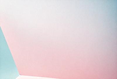 The primary subject of the image is a large, empty white wall. The setting is a room with a pink background, which adds a warm and inviting atmosphere to the scene. The visual style of the image is a photo, capturing the stark contrast between the white wall and the pink background. The colors and mood of the image are predominantly pink and white, creating a sense of calmness and simplicity.