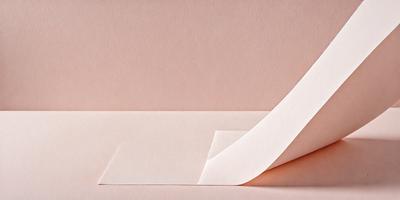 The primary subject of the image is a piece of paper, which is the main object, scene, or focus of the image. The paper is placed on a pink surface, which serves as the setting or background. The visual style of the image is a photo, as it captures the paper's texture and details. The colors in the image are predominantly pink, creating a warm and inviting atmosphere.
