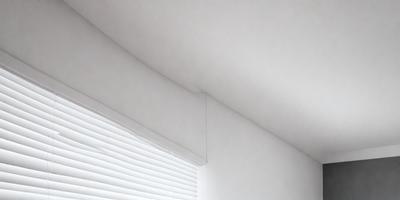 The primary subject of the image is a white shade hanging from a window. The setting is a room with a white ceiling, and the visual style is a photo. The colors and mood of the image are predominantly white, creating a clean and minimalist atmosphere.