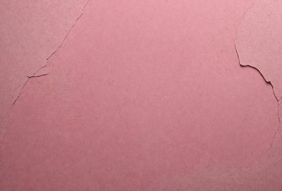 The primary subject of the image is a pink wall with a peeling paint surface. The setting is a room with a pink background. The visual style is a close-up of the pink wall, showcasing the peeling paint. The colors and mood of the image are predominantly pink, giving it a warm and inviting atmosphere.