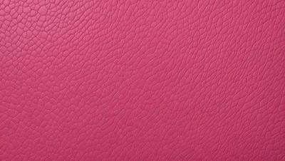 The primary subject of the image is a close-up of a pink leather surface. The setting is a room with a pink background. The visual style is a photo, and the colors and mood are predominantly pink, creating a warm and inviting atmosphere.