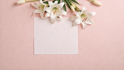 The primary subject of the image is a white card with a blank space on it, surrounded by a bouquet of white flowers. The setting is a pink background, which adds a touch of color to the scene. The visual style is a combination of a photo and digital art, as the flowers and card appear to be realistic yet have a slightly artificial quality. The colors and mood of the image are predominantly white and pink, creating a sense of elegance and simplicity.