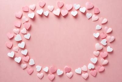 The primary subject of the image is a pink heart-shaped paper with a circle of hearts around it. The hearts are made of paper and are scattered around the pink heart, creating a visually appealing and heartwarming scene. The setting is a pink background, which complements the color of the hearts. The visual style is a combination of digital art and illustration, as the hearts are carefully arranged and the overall composition is well-executed. The colors and mood of the image are predominantly p