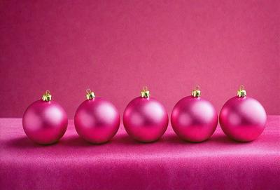 The primary subject of the image is a row of six pink ornaments, which are likely Christmas ornaments. They are arranged in a straight line on a pink surface, which could be a table or a wall. The setting appears to be indoors, and the visual style is a close-up of the ornaments. The colors and mood of the image are predominantly pink, creating a warm and festive atmosphere.