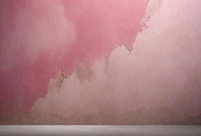 The primary subject of the image is a pink wall with a peeling paint effect. The setting is a room with a pink wall, and the visual style is a photo. The dominant colors are pink and red, creating a warm and inviting atmosphere.