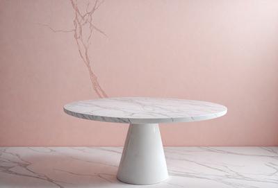 The primary subject of the image is a white round table with a marble top. The table is placed on a marble floor, which serves as the setting for the scene. The visual style of the image is a photo, capturing the details of the table and floor. The colors and mood of the image are predominantly white, giving it a clean and elegant appearance.