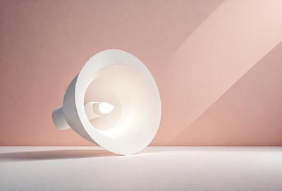 The primary subject of the image is a white light bulb, which is the main object in the scene. The light bulb is placed on a pink surface, creating a contrast between the white light bulb and the pink background. The visual style of the image is a photo, capturing the light bulb in its natural environment. The colors and mood of the image are predominantly white and pink, giving it a warm and inviting atmosphere.