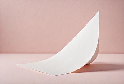 The primary subject of the image is a white paper boat, which is the main object, scene, or focus of the image. The setting is a pink surface, which serves as the backdrop for the paper boat. The visual style of the image is a photo, capturing the details of the paper boat. The colors and mood of the image are predominantly pink, creating a warm and inviting atmosphere.