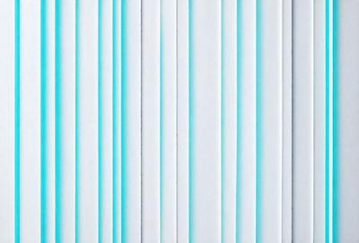 The primary subject of the image is a long row of white stripes. The setting is a white background, and the visual style appears to be a pattern or texture. The dominant colors are white, and the overall atmosphere is clean and minimalistic.