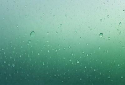 The primary subject of the image is a rainy scene with a green background. The setting is a rainy day, and the visual style is a photo. The colors and mood of the image are dominated by the green hue of the rain and the overall atmosphere is calm and serene.