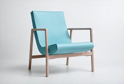 The primary subject of the image is a blue chair with a leather seat. The chair is placed on a white surface, which serves as the setting or background. The visual style of the image is a photo, capturing the chair in its natural environment. The colors and mood of the image are predominantly blue and white, creating a clean and minimalist atmosphere.