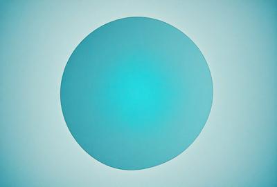 The primary subject of the image is a large, round, blue circle. The setting is a white background, which provides a clean and minimalist appearance. The visual style is a digital art or illustration, as the circle appears to be a stylized, abstract representation of a blue sphere. The colors and mood of the image are predominantly blue, creating a calm and serene atmosphere.