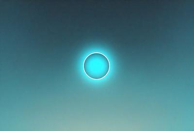 The primary subject of the image is a blue circle, which appears to be a sun or a moon. The setting is a dark blue sky, and the visual style is a photo. The dominant colors are blue and black, creating a calm and serene atmosphere.