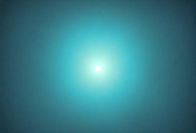 The primary subject of the image is a bright, white light in the middle of a dark, blue sky. The light appears to be a sun or a moon, depending on the viewer's perspective. The setting is a vast, open space with no visible landmarks or objects. The visual style is a combination of a photo and a digital art, as the light appears to be a digital manipulation of the sky. The colors and mood of the image are predominantly dark and moody, with the bright white light standing out