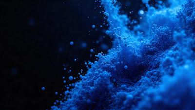 The primary subject of the image is a blue substance, which appears to be a powder or a liquid, as it is either falling or being blown upward. The setting is a dark background, which contrasts with the blue substance, making it stand out. The visual style of the image is a close-up of the blue substance, showcasing its texture and details. The colors and mood of the image are predominantly blue, creating a sense of depth and tranquility.