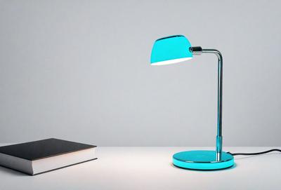 The primary subject of the image is a blue desk lamp. The lamp is placed on a white table, which serves as the setting for the scene. The visual style of the image is a photo, capturing the lamp's light and color. The dominant colors in the image are blue and white, creating a calm and soothing atmosphere.