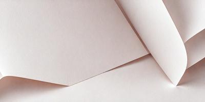 The primary subject of the image is a piece of white paper. The setting is a table, and the visual style is a close-up of the paper. The colors and mood of the image are predominantly white, giving it a clean and simple appearance.