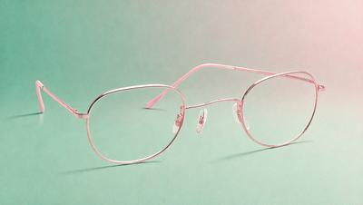 The primary subject of the image is a pair of glasses, which are placed on a green surface. The glasses are positioned in a way that they appear to be floating or hovering above the surface. The setting is a green background, which provides a contrasting and visually appealing backdrop for the glasses. The visual style of the image is a close-up of the glasses, showcasing their design and details. The colors and mood of the image are predominantly green, creating a calm and ser