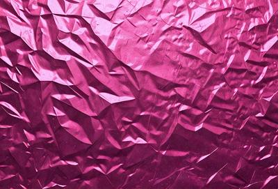 The primary subject of the image is a pink, shiny, and textured surface. The setting is a close-up of the surface, which appears to be a piece of pink fabric or a patterned material. The visual style is a combination of a photo and a digital art, illustration, or drawing. The colors and mood of the image are predominantly pink, creating a warm and inviting atmosphere.