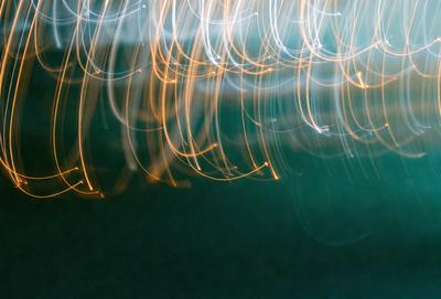 The primary subject of the image is a brightly lit scene featuring a large number of light streaks or sparkles. The setting appears to be a dark room, and the visual style is a combination of a photo and digital art. The colors in the image are predominantly yellow, and the overall atmosphere is lively and energetic.
