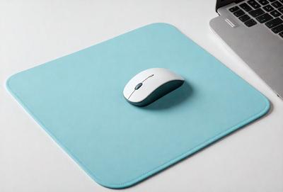 The primary subject of the image is a white computer mouse. The mouse is placed on a blue mouse pad, which is sitting on a white surface. The visual style of the image is a photo, and the dominant colors are blue and white. The overall atmosphere of the image is clean and organized, with the mouse and mouse pad being the main focus.