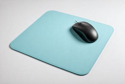 The primary subject of the image is a black and grey computer mouse. The mouse is placed on a blue mouse pad, which is sitting on a white surface. The visual style of the image is a photo, and the dominant colors are blue and grey. The overall atmosphere of the image is clean and modern.