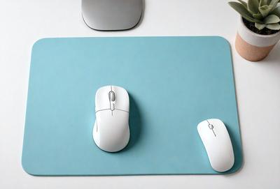 The primary subject of the image is a white computer mouse. The mouse is placed on a blue mouse pad, which is situated on a white surface. The visual style of the image is a photo, and the dominant colors are blue and white. The overall atmosphere of the image is clean and organized, with the mouse and mouse pad being the main focus.