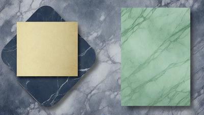 The primary subject of the image is a square piece of paper with a blue border. The paper is placed on a marble surface, which serves as the setting and background. The visual style of the image is a photo, and the dominant colors are blue and green. The overall atmosphere of the image is elegant and sophisticated.