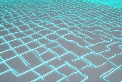 The primary subject of the image is a blue, light-filled surface that appears to be a water-like environment. The setting is a large, open space with a blue, rippled surface that resembles water. The visual style of the image is a digital art or illustration, as it is a computer-generated or digitally created image. The colors and mood of the image are predominantly blue, creating a serene and calming atmosphere.