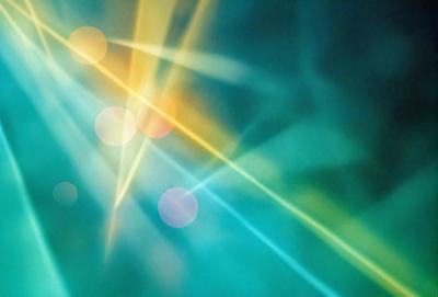 The primary subject of the image is a brightly colored, abstract pattern of light and color. The setting is a dark background, which contrasts with the vibrant colors of the pattern. The visual style is a combination of digital art and illustration, creating a dynamic and eye-catching design. The dominant colors are green, yellow, and orange, giving the image a lively and energetic atmosphere.
