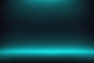 The primary subject of the image is a blue background with a dark, almost black, surface. The setting appears to be a dark room or a space with a blue-toned atmosphere. The visual style of the image is a close-up of the blue background, which gives it a unique and artistic appearance. The colors and mood of the image are predominantly blue, creating a calm and serene atmosphere.