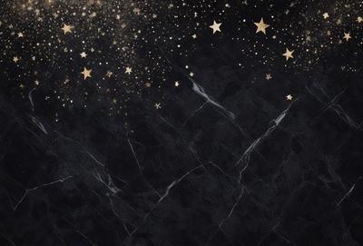 The primary subject of the image is a black marble countertop with a starry night sky background. The setting is a dark, star-filled sky, creating a dramatic and atmospheric backdrop. The visual style is a combination of a photo and digital art, as the image features a realistic marble countertop and a starry night sky, but the overall atmosphere is more artistic and surreal. The colors and mood of the image are predominantly dark, with the starry night sky providing a sense of