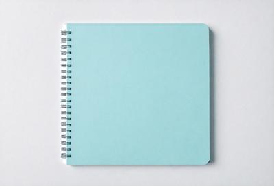 The primary subject of the image is a blue spiral notebook. The setting is a white background, and the visual style is a photo. The notebook is open, and the dominant colors are blue and white. The overall atmosphere is calm and organized.