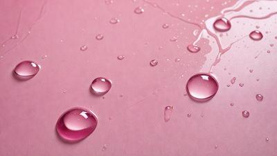 The primary subject of the image is a pink surface with water droplets on it. The setting is a pink background, and the visual style is a photo. The colors and mood of the image are predominantly pink, creating a warm and inviting atmosphere.