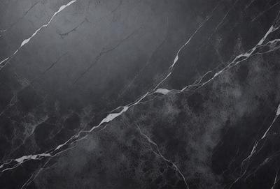 The primary subject of the image is a marble-like surface with a patterned texture. The setting is a black background, which contrasts with the marble-like surface. The visual style is a close-up of the marble-like surface, showcasing its intricate pattern. The colors and mood of the image are predominantly dark, with the marble-like surface providing a sense of depth and sophistication.