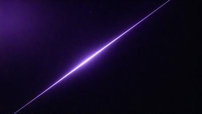 The primary subject of the image is a purple light streak, which appears to be a line or a beam of light. The setting is a dark, starry night sky, with the purple light streak as the main focus. The visual style of the image is a combination of a photo and a digital art, creating a unique and captivating scene. The colors and mood of the image are predominantly purple, which gives it a mysterious and enchanting atmosphere.