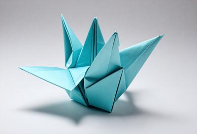 The primary subject of the image is a blue origami crane, which is a paper bird crafted from a square sheet of paper. The setting is a white background, which provides a clean and minimalist look. The visual style is a combination of art and craftsmanship, as the origami crane is a traditional Japanese art form. The colors and mood of the image are predominantly blue, which gives the scene a calm and serene atmosphere.