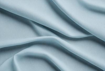 The primary subject of the image is a blue fabric, which appears to be a piece of leather. The setting is a blue background, and the visual style is a close-up of the fabric. The colors and mood of the image are predominantly blue, creating a calm and serene atmosphere.