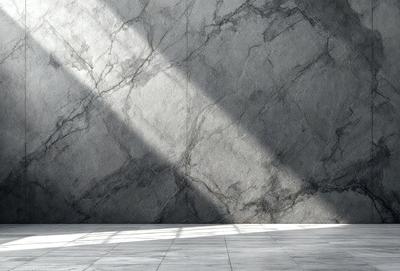 The primary subject of the image is a large, gray stone wall. The setting is a room with a white floor, and the visual style is a photo. The dominant colors are gray and white, creating a clean and minimalist atmosphere.